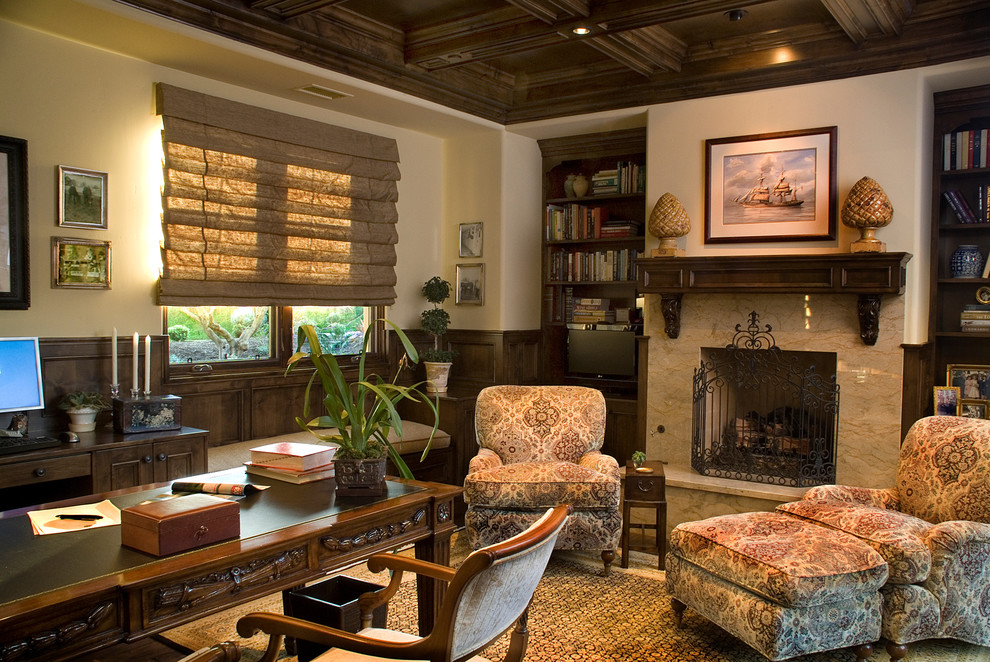Photo of a large traditional home office in San Diego with beige walls, dark hardwood floors, a standard fireplace and a freestanding desk.