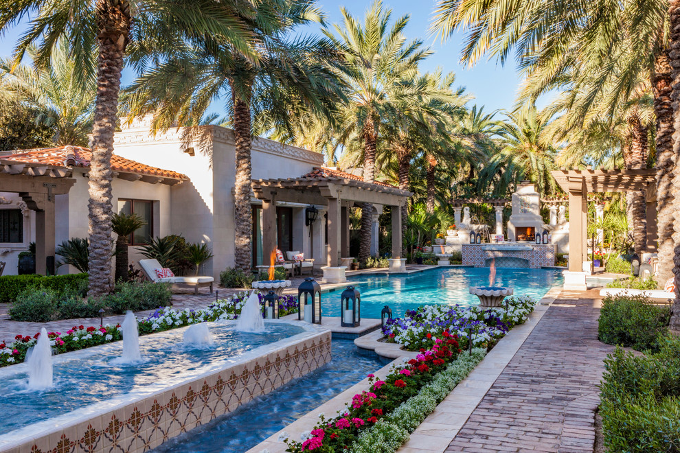 Photo of a mediterranean courtyard rectangular lap pool in Phoenix with a water feature and brick pavers.