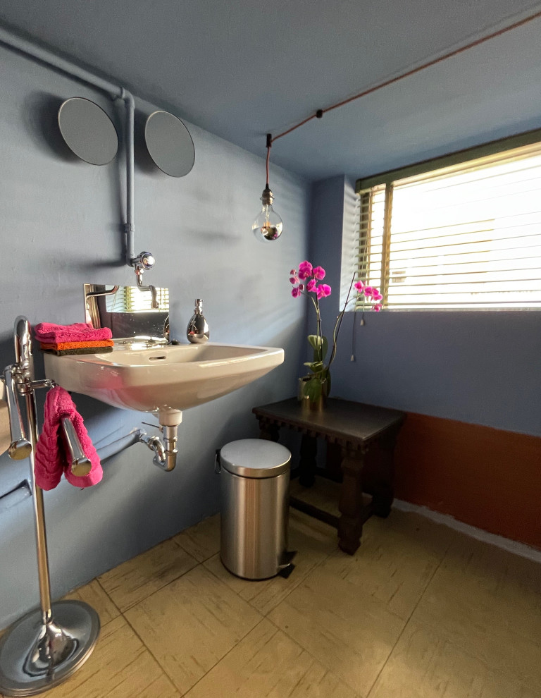 This is an example of a small eclectic powder room in Other with blue walls, linoleum floors, a wall-mount sink and beige floor.