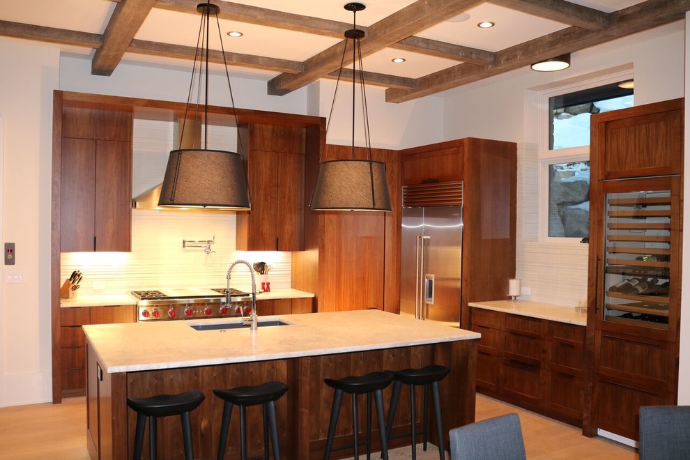 Photo of a mid-sized country l-shaped eat-in kitchen in Denver with a drop-in sink, medium wood cabinets, beige splashback, light hardwood floors, with island, shaker cabinets and stainless steel appliances.