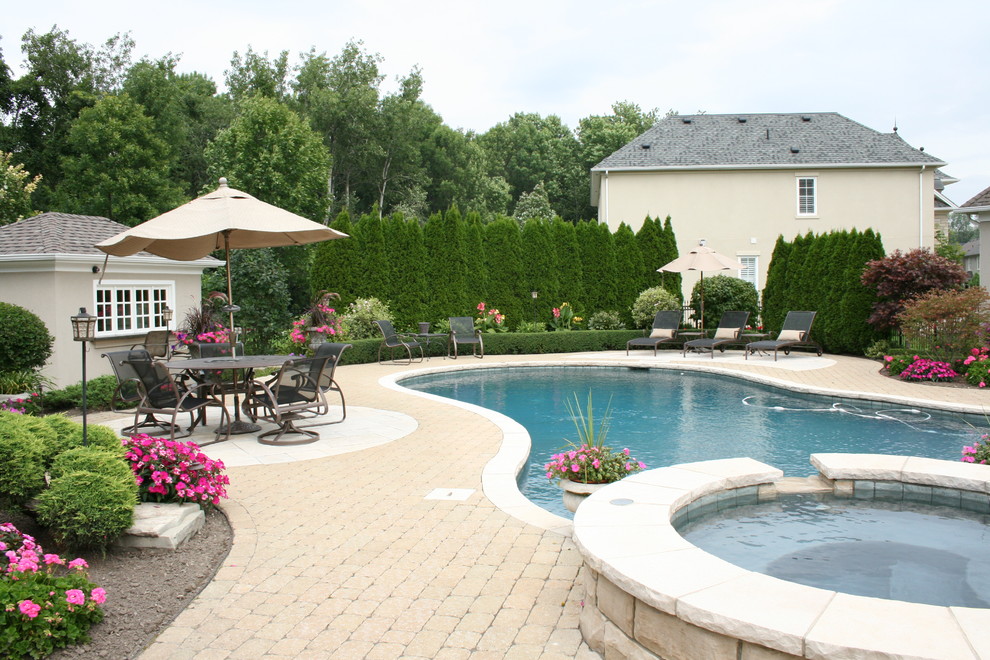 Example of a large transitional backyard brick and custom-shaped hot tub design in Toronto