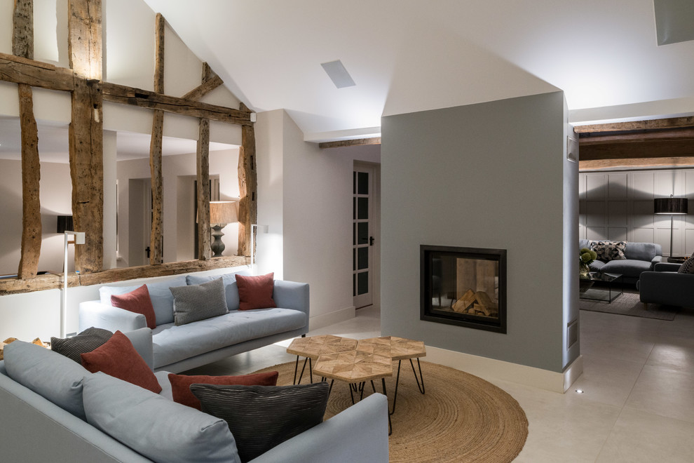This is an example of a large country open concept living room in Other with white walls, limestone floors, a two-sided fireplace, a metal fireplace surround and white floor.