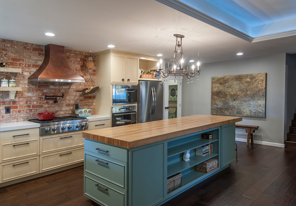 Mid-sized eclectic l-shaped open plan kitchen in San Francisco with a farmhouse sink, raised-panel cabinets, blue cabinets, quartz benchtops, red splashback, stainless steel appliances, medium hardwood floors and with island.