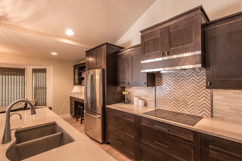 Example of a large transitional l-shaped light wood floor eat-in kitchen design in Phoenix with an undermount sink, shaker cabinets, dark wood cabinets, quartz countertops, beige backsplash, matchstick tile backsplash, stainless steel appliances and an island