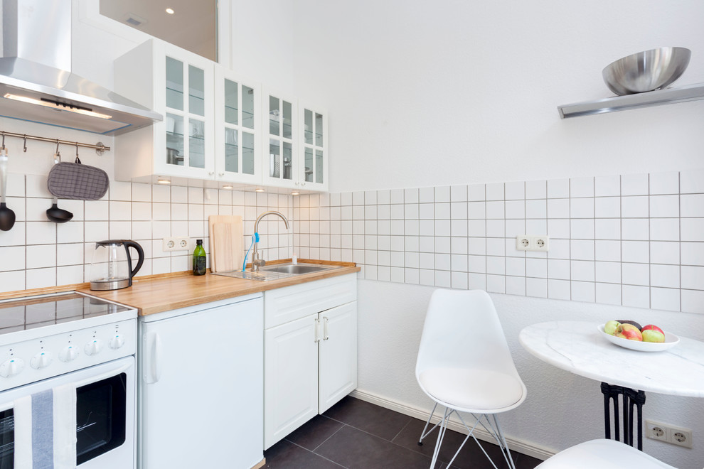 This is an example of a small scandinavian single-wall eat-in kitchen in Other with a drop-in sink, raised-panel cabinets, white cabinets, white splashback, ceramic splashback, white appliances, laminate benchtops, no island and black floor.
