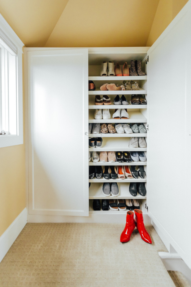 This is an example of a small transitional gender-neutral storage and wardrobe in Other with shaker cabinets, white cabinets, carpet, beige floor and vaulted.