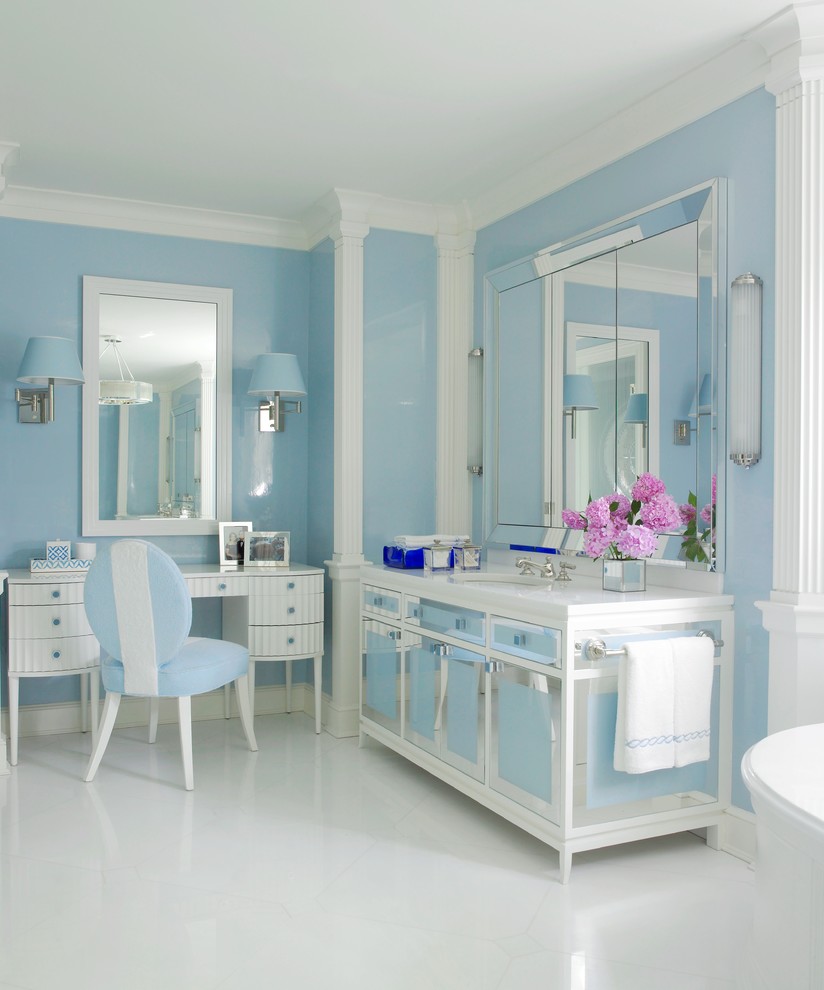 Photo of a beach style master bathroom in New York with an undermount sink, blue walls and glass-front cabinets.