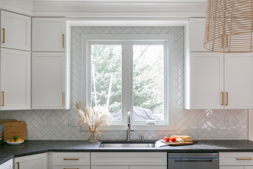 Inspiration for a large transitional l-shaped brown floor kitchen pantry remodel in Baltimore with a drop-in sink, shaker cabinets, white cabinets, quartz countertops, white backsplash, ceramic backsplash, stainless steel appliances, an island and white countertops