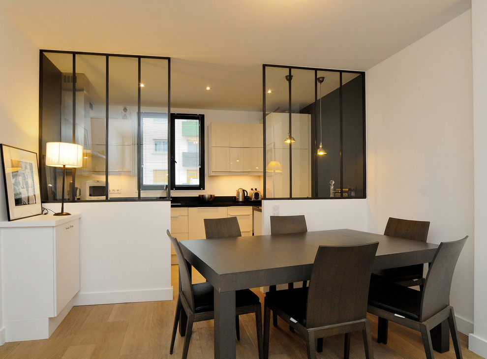 Photo of a mid-sized contemporary kitchen/dining combo in Paris with white walls, medium hardwood floors and no fireplace.