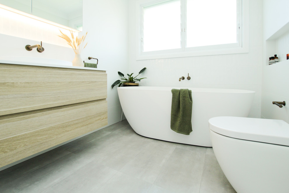 Photo of a mid-sized modern master bathroom in Sydney with light wood cabinets, a freestanding tub, an open shower, a one-piece toilet, white tile, grey floor, an open shower, white benchtops, a niche, a single vanity and a floating vanity.