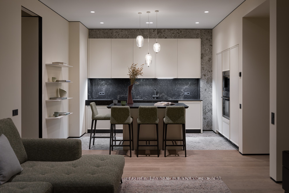 Photo of a mid-sized contemporary single-wall separate kitchen in Other with an undermount sink, raised-panel cabinets, white cabinets, marble benchtops, black splashback, marble splashback, black appliances, porcelain floors, with island, black floor and black benchtop.