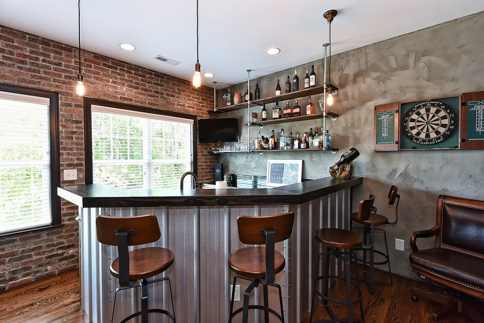 Mid-sized industrial u-shaped seated home bar in Other with an undermount sink, open cabinets, dark hardwood floors, brown floor and black benchtop.