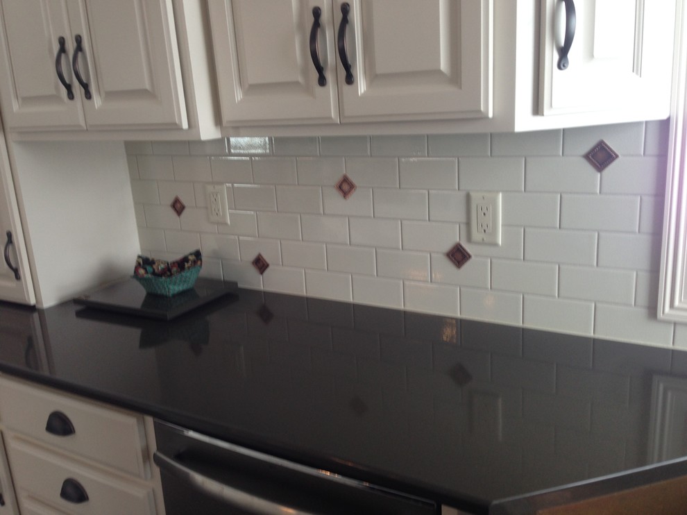 Example of a mid-sized classic l-shaped dark wood floor and black floor open concept kitchen design with a farmhouse sink, raised-panel cabinets, white cabinets, quartz countertops, white backsplash, ceramic backsplash, stainless steel appliances and an island