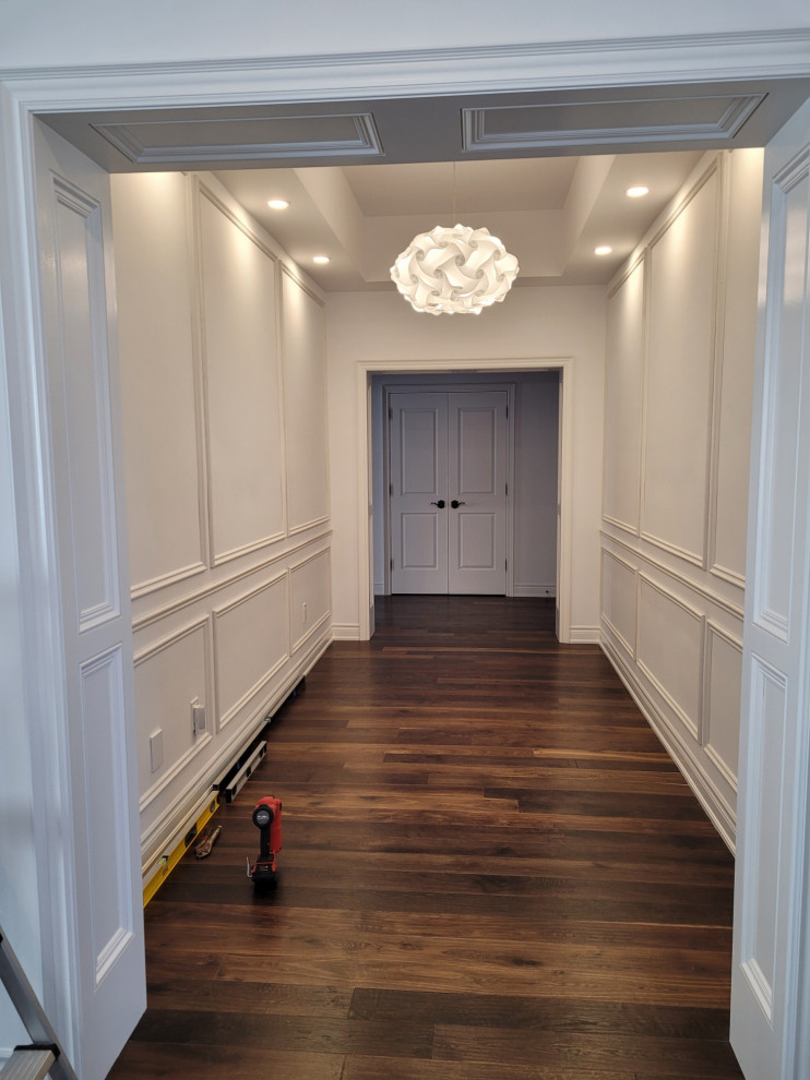 Cette image montre un couloir design avec un mur blanc, un sol en bois brun, un sol marron, un plafond à caissons et boiseries.