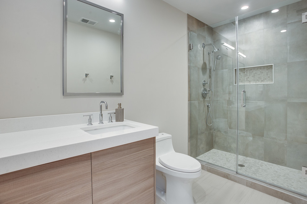 Photo of a small modern master bathroom in DC Metro with flat-panel cabinets, brown cabinets, a one-piece toilet, gray tile, porcelain tile, grey walls, porcelain floors, an undermount sink, engineered quartz benchtops, grey floor, a hinged shower door and yellow benchtops.