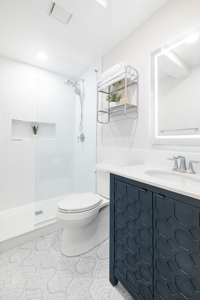Medium sized coastal ensuite bathroom in DC Metro with freestanding cabinets, white tiles, porcelain tiles, white worktops, a wall niche, a single sink, blue cabinets, an alcove shower, grey walls, porcelain flooring, a submerged sink, engineered stone worktops, blue floors, an open shower and a freestanding vanity unit.
