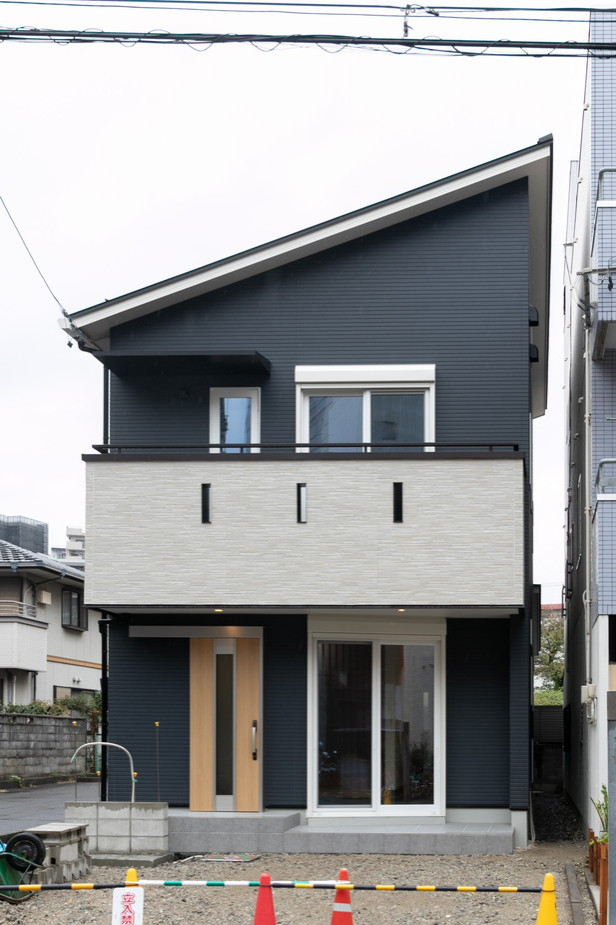 Foto della facciata di una casa nera moderna a due piani con copertura in metallo o lamiera e tetto nero