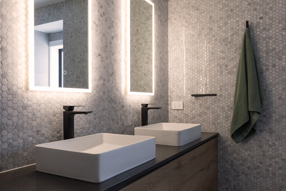 This is an example of a mid-sized contemporary master bathroom in Auckland with medium wood cabinets, an open shower, mosaic tile, a vessel sink, engineered quartz benchtops, an open shower, black benchtops, a double vanity and a floating vanity.