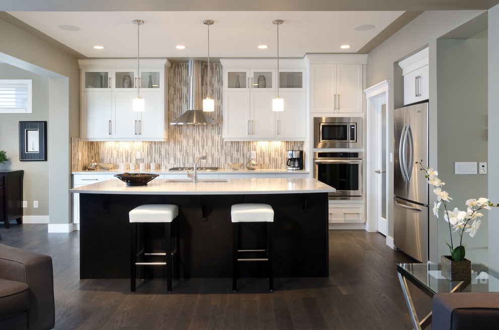 Mid-sized traditional single-wall eat-in kitchen in Calgary with recessed-panel cabinets, white cabinets, stainless steel appliances, dark hardwood floors and with island.