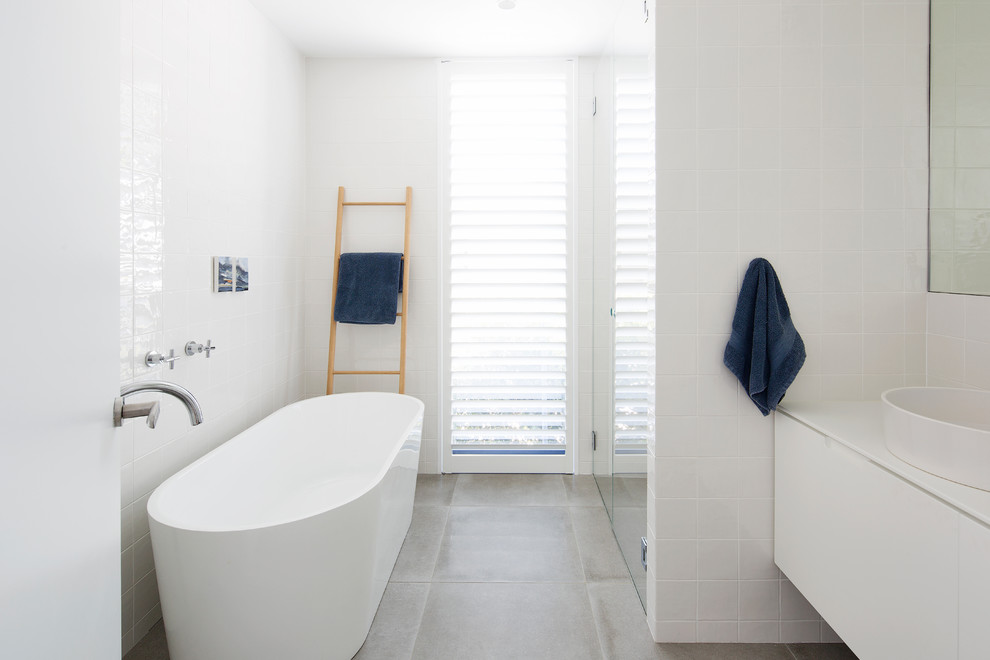 Inspiration for a contemporary 3/4 bathroom in Sydney with flat-panel cabinets, white cabinets, a freestanding tub, a curbless shower, white tile, a vessel sink, grey floor and a hinged shower door.