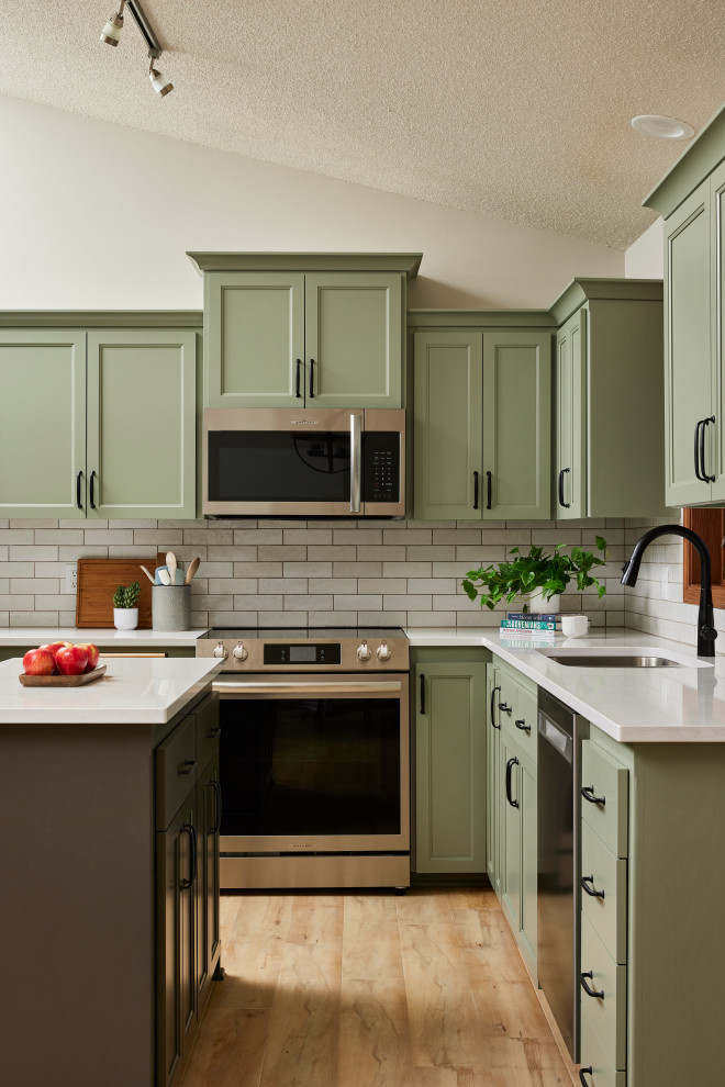 Example of a mid-sized transitional u-shaped vinyl floor and brown floor eat-in kitchen design in Minneapolis with an undermount sink, shaker cabinets, green cabinets, quartz countertops, white backsplash, ceramic backsplash, stainless steel appliances, an island and white countertops