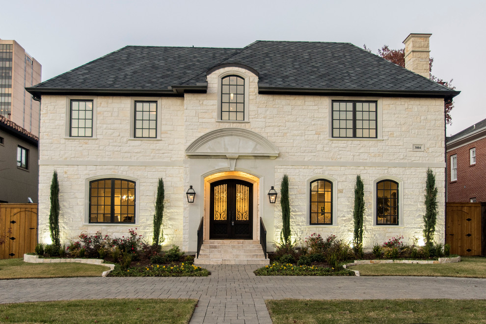 This is an example of a mid-sized transitional two-storey beige exterior in Dallas with stone veneer and a hip roof.