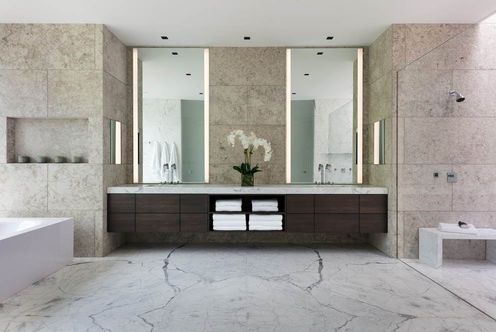 This is an example of a large modern master wet room bathroom with flat-panel cabinets, light wood cabinets, a freestanding tub, a wall-mount toilet, beige tile, cement tile, beige walls, an undermount sink, granite benchtops and marble floors.