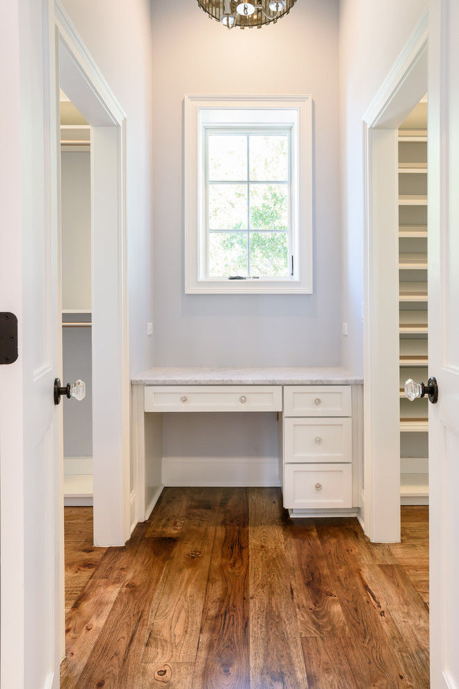 Inspiration for a mid-sized beach style gender-neutral walk-in wardrobe in Jacksonville with shaker cabinets, white cabinets and medium hardwood floors.