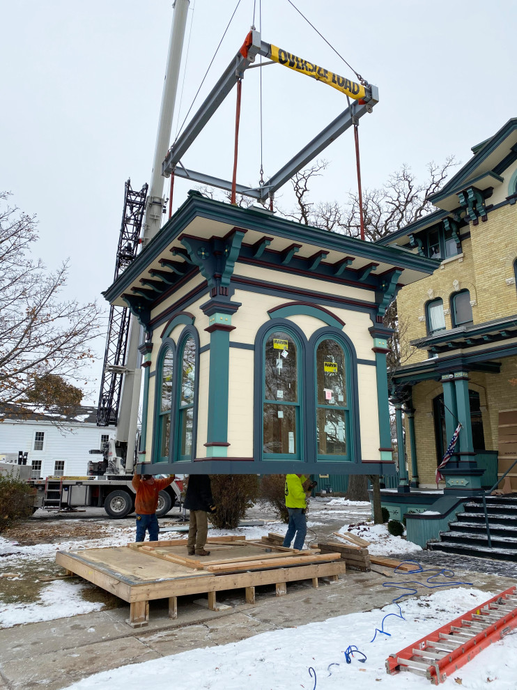 Inspiration for a large victorian beige four-story brick house exterior remodel in Milwaukee with a metal roof