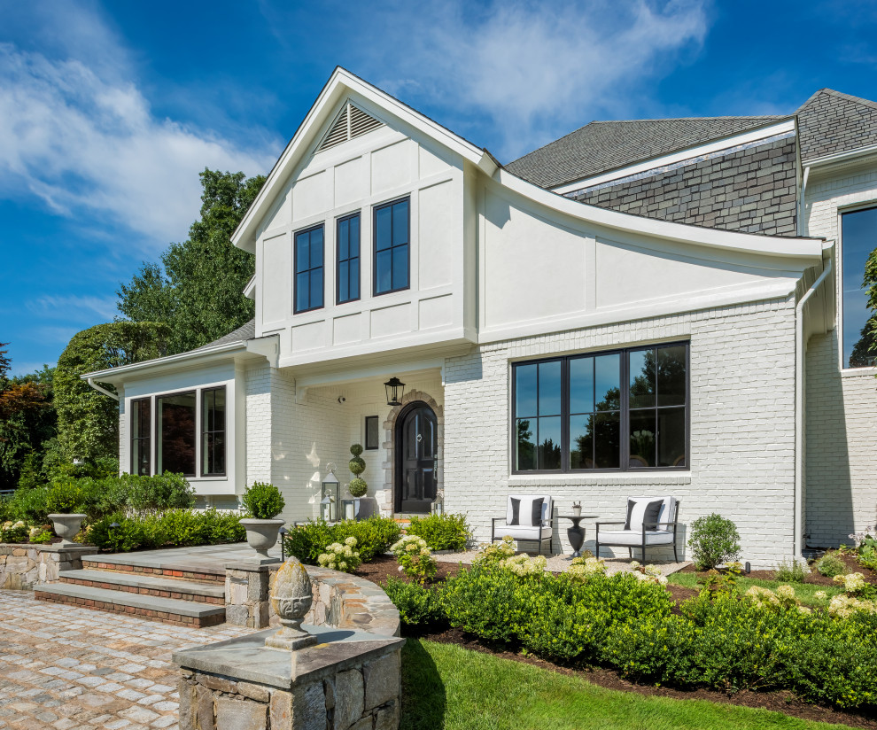 Expansive transitional two-storey brick white house exterior in Providence with a shingle roof.