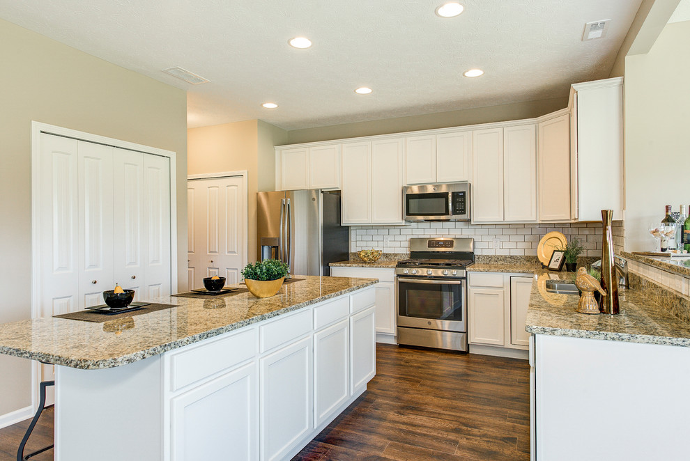 Mid-sized transitional l-shaped medium tone wood floor and brown floor eat-in kitchen photo in Chicago with an undermount sink, recessed-panel cabinets, white cabinets, granite countertops, white backsplash, subway tile backsplash, stainless steel appliances, two islands and brown countertops