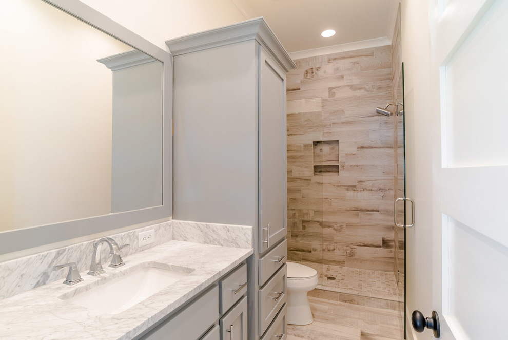 Inspiration for a large beach style 3/4 bathroom in Other with shaker cabinets, grey cabinets, white walls, ceramic floors, an undermount sink, marble benchtops, an alcove shower, brown tile, porcelain tile, beige floor and a hinged shower door.