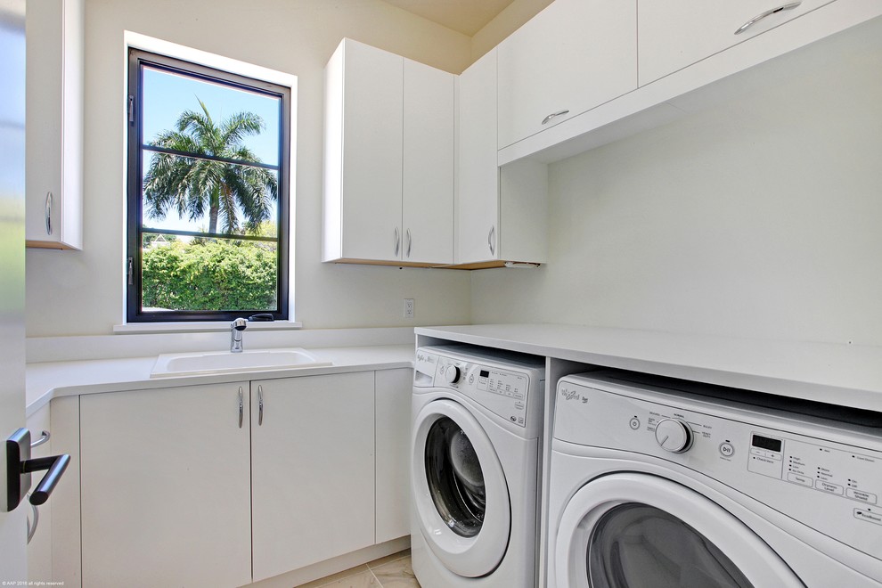 Photo of a mid-sized mediterranean u-shaped dedicated laundry room in Miami with white walls and a side-by-side washer and dryer.