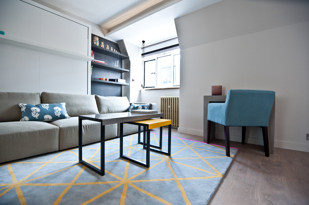 This is an example of a small contemporary enclosed living room in London with grey walls, light hardwood floors, no fireplace and a wall-mounted tv.