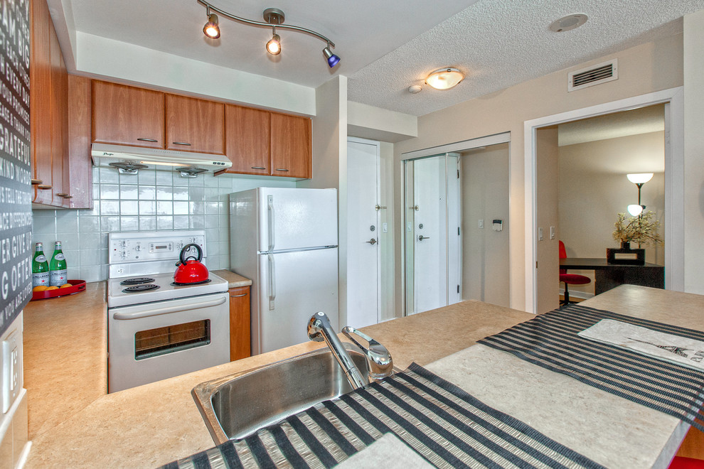 Small transitional u-shaped ceramic tile eat-in kitchen photo in Toronto with a drop-in sink, flat-panel cabinets, medium tone wood cabinets, solid surface countertops, white backsplash, subway tile backsplash, white appliances and a peninsula