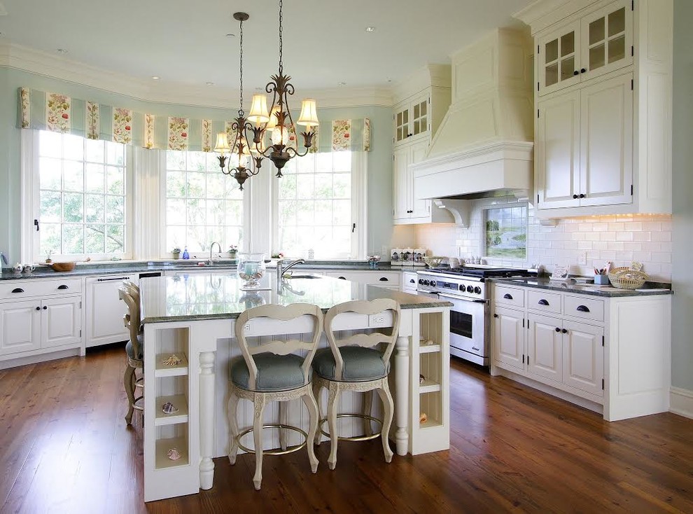 Photo of a traditional l-shaped kitchen in Raleigh with raised-panel cabinets, white cabinets, white splashback, subway tile splashback, stainless steel appliances, medium hardwood floors, with island and granite benchtops.