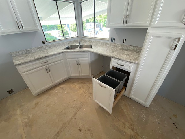 Eat-in kitchen - mid-sized l-shaped eat-in kitchen idea with a double-bowl sink, flat-panel cabinets, white cabinets, laminate countertops, an island and gray countertops
