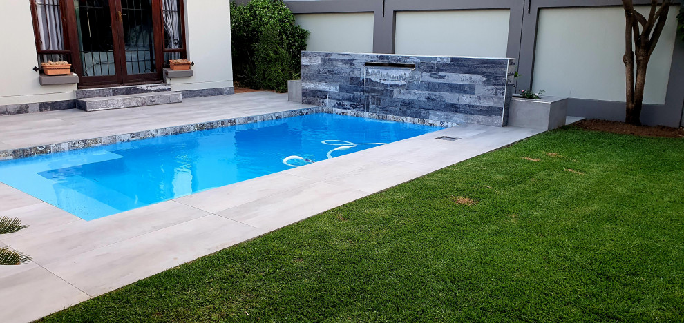 Diseño de piscina con fuente mediterránea de tamaño medio rectangular en patio con suelo de baldosas