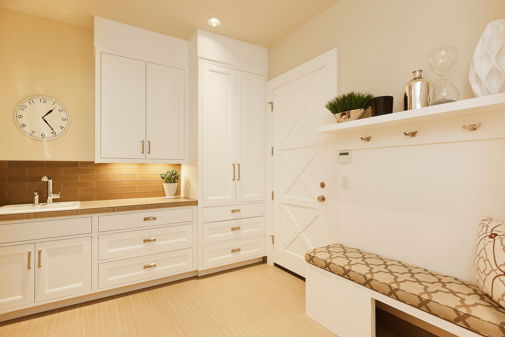 This is an example of a mid-sized transitional l-shaped dedicated laundry room in Portland with a drop-in sink, recessed-panel cabinets, white cabinets, beige walls, beige floor, solid surface benchtops, porcelain floors and beige benchtop.
