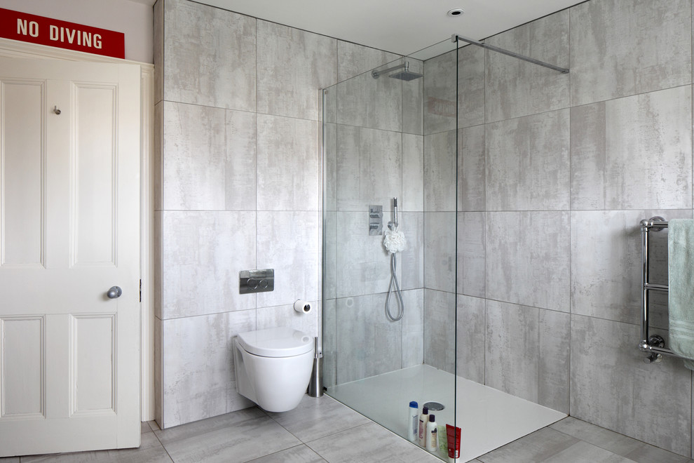 Large scandinavian kids bathroom in Sussex with flat-panel cabinets, white cabinets, a freestanding tub, an open shower, a wall-mount toilet, gray tile, ceramic tile, grey walls, ceramic floors and a wall-mount sink.