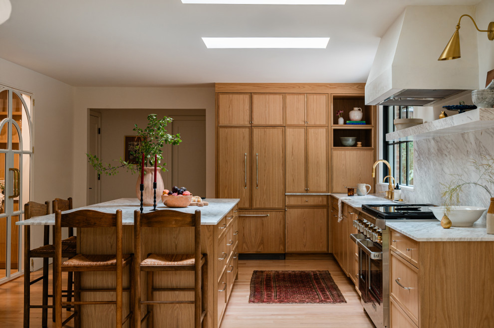 Eat-in kitchen - mid-sized transitional l-shaped light wood floor eat-in kitchen idea in Chicago with an undermount sink, shaker cabinets, light wood cabinets, marble countertops, white backsplash, marble backsplash, paneled appliances, an island and white countertops