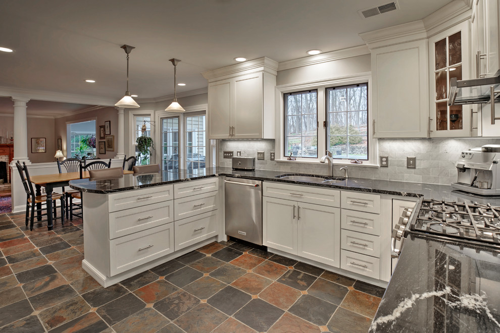 This is an example of a mid-sized transitional u-shaped eat-in kitchen in New York with an undermount sink, recessed-panel cabinets, white cabinets, granite benchtops, grey splashback, subway tile splashback, stainless steel appliances, slate floors, a peninsula and multi-coloured floor.