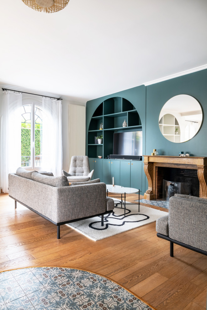 Großes, Offenes Modernes Wohnzimmer mit grüner Wandfarbe, hellem Holzboden, Kamin, Kaminumrandung aus Stein, TV-Wand, braunem Boden und vertäfelten Wänden in Paris