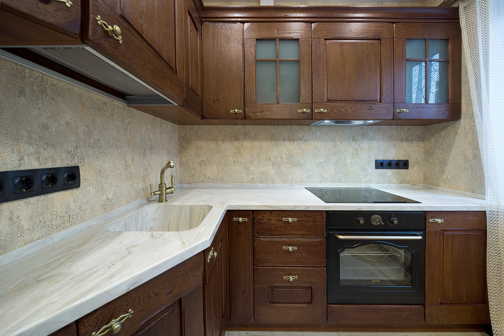 Photo of a mid-sized country l-shaped eat-in kitchen in Saint Petersburg with a single-bowl sink, raised-panel cabinets, dark wood cabinets, solid surface benchtops and black appliances.