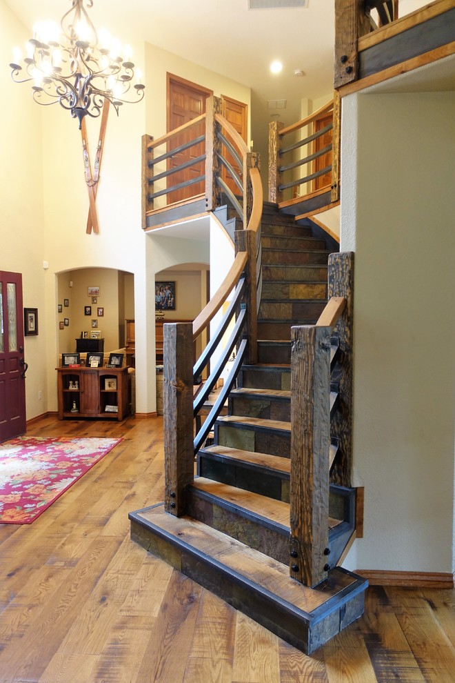 Large country wood curved staircase in Denver with slate risers and wood railing.