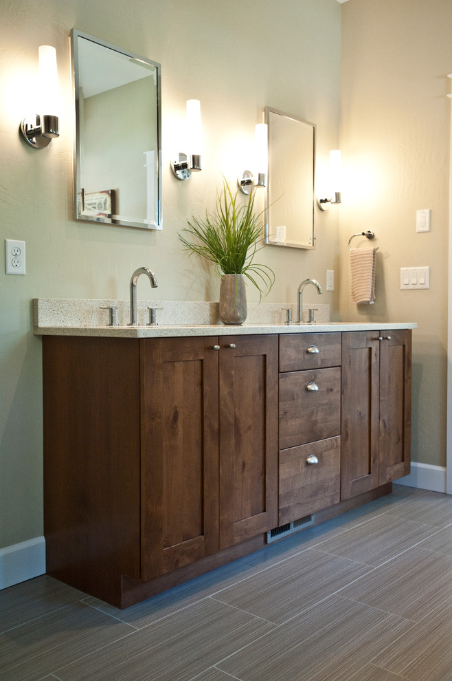 Inspiration for a large transitional master gray tile and ceramic tile ceramic tile drop-in bathtub remodel with an undermount sink, shaker cabinets, brown cabinets, quartz countertops and gray walls