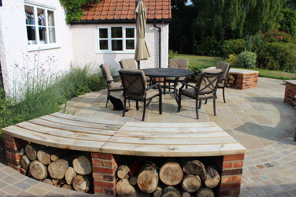 Photo of a mid-sized traditional backyard patio in Hertfordshire with natural stone pavers.