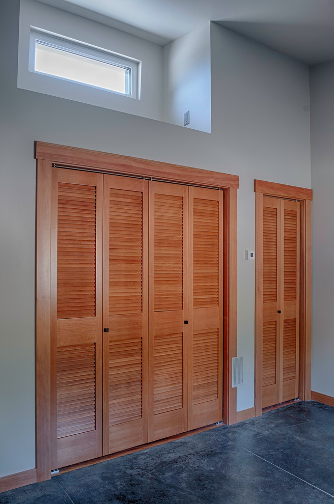 Mid-sized contemporary gender-neutral built-in wardrobe in Seattle with louvered cabinets, medium wood cabinets and concrete floors.