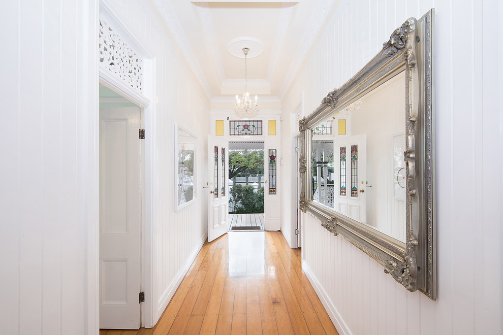 This is an example of a traditional hallway in Brisbane with white walls and medium hardwood floors.