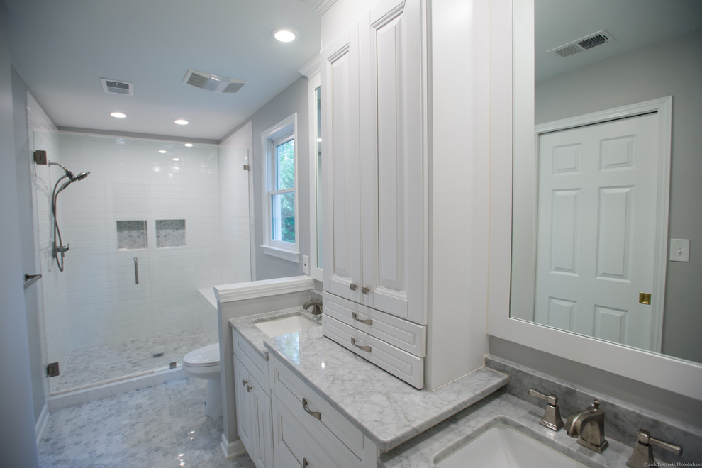 This is an example of a mid-sized transitional master bathroom in Atlanta with shaker cabinets, white cabinets, an alcove shower, a one-piece toilet, white tile, subway tile, grey walls, mosaic tile floors, an undermount sink and marble benchtops.